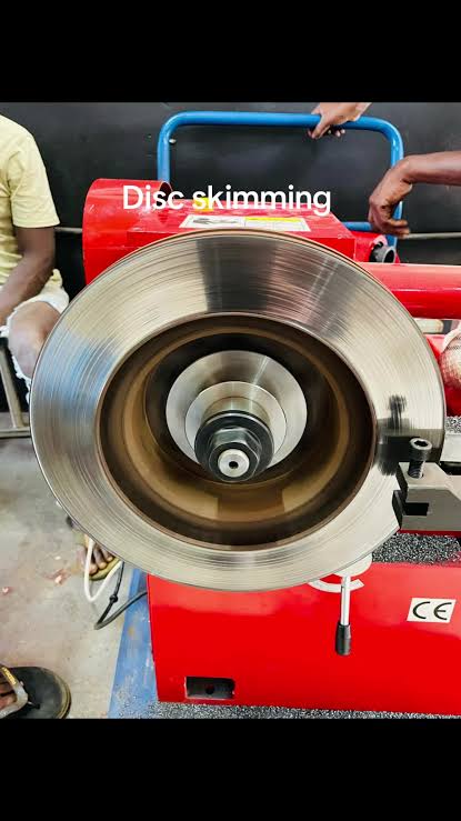 Brake disc mounted on a red workshop lathe