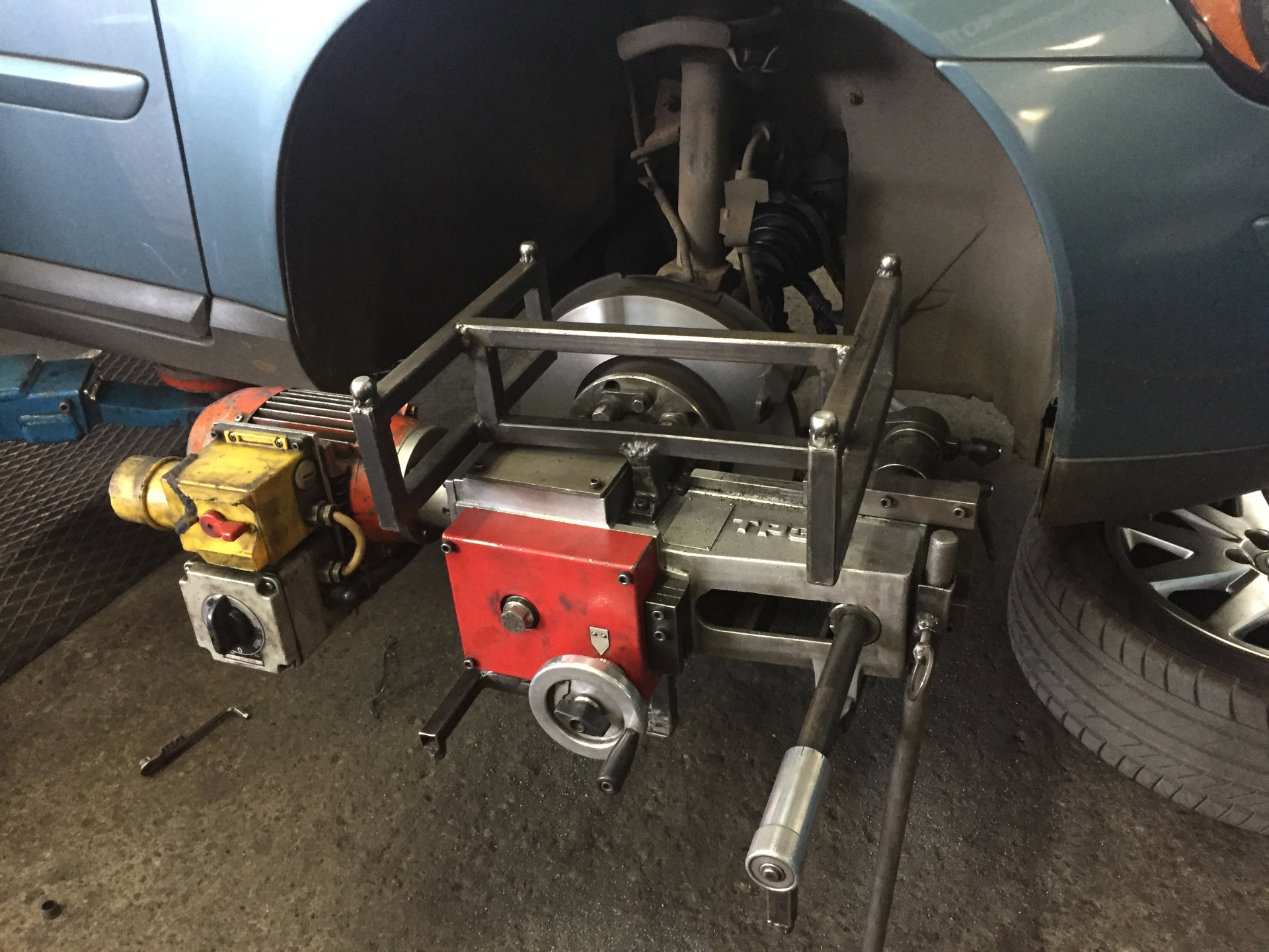 On-car brake lathe attached to a vehicle with its wheel removed